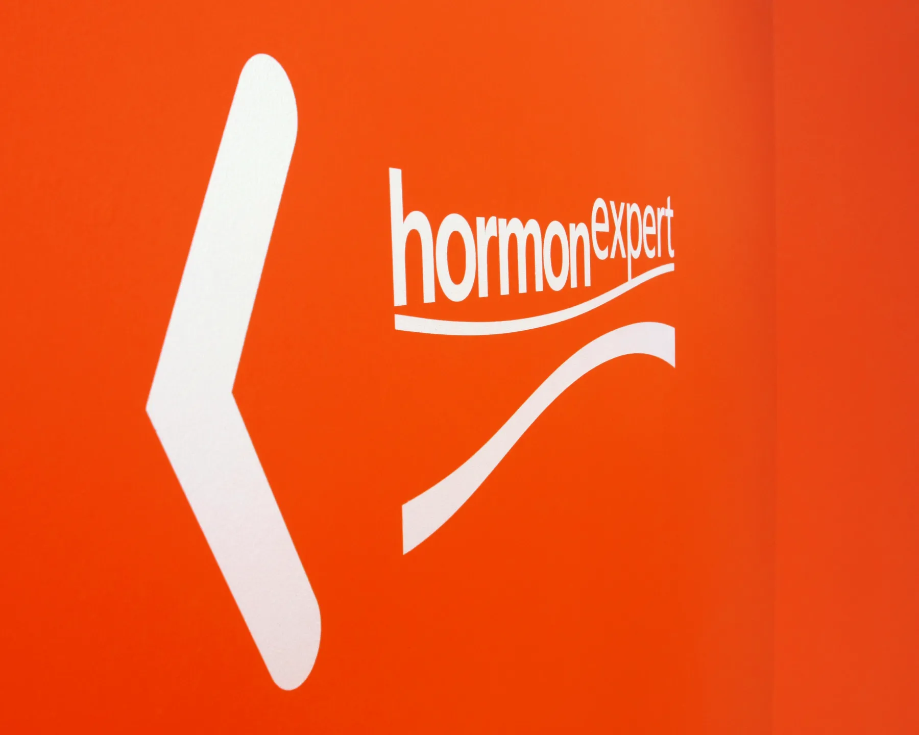 Hormonexpert-Logo in Weiß auf orangefarbenem Hintergrund als Element des Leitsystems.