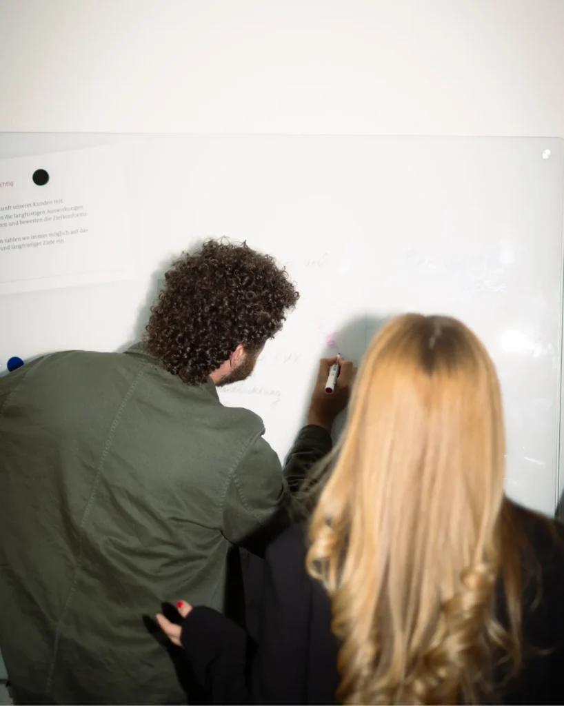 Zwei Teammitglieder der Werbeagentur Schlösser & Co. bei der Konzeption einer Website am Whiteboard.